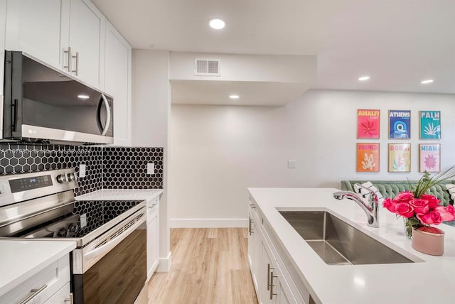 kitchen featuring white cabinets, tasteful backsplash, light hardwood / wood-style flooring, sink, and stainless steel appliances