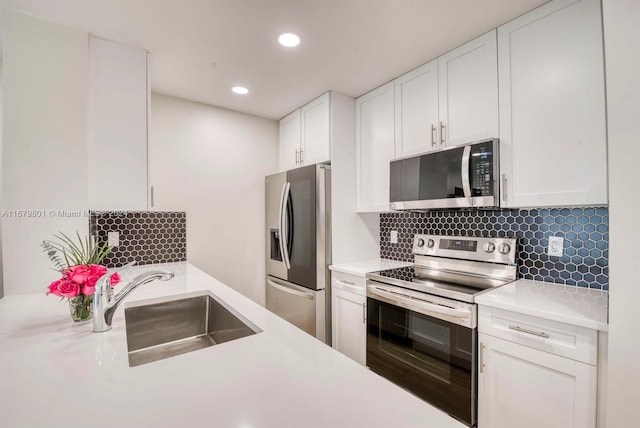 kitchen featuring appliances with stainless steel finishes, white cabinets, tasteful backsplash, and sink