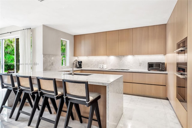 kitchen featuring light brown cabinets, kitchen peninsula, a healthy amount of sunlight, and a breakfast bar area