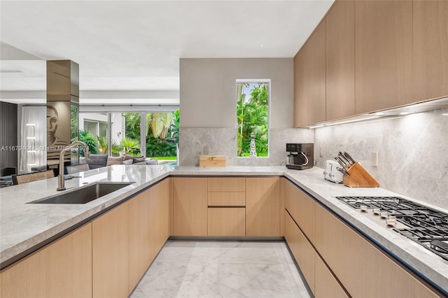 kitchen with stainless steel gas cooktop, tasteful backsplash, sink, and light brown cabinets