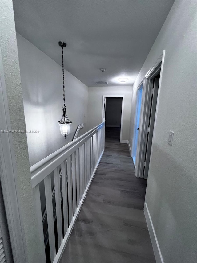 hall with dark wood-type flooring and a notable chandelier