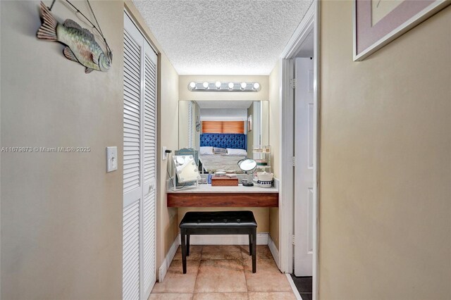 hall with a textured ceiling and light tile patterned flooring