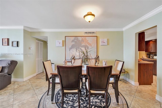 dining space featuring crown molding and light tile patterned floors