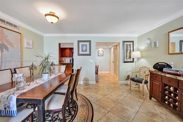 dining space featuring ornamental molding and light tile patterned floors