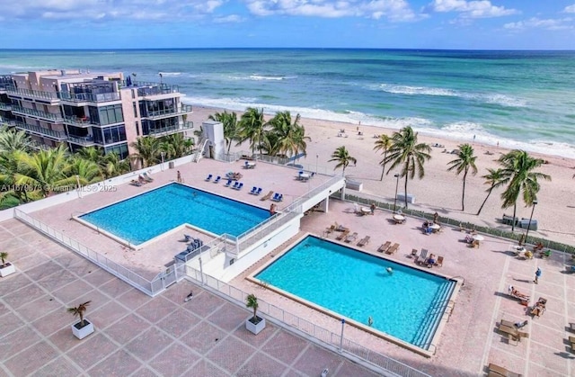 view of pool with a water view, a patio, and a view of the beach