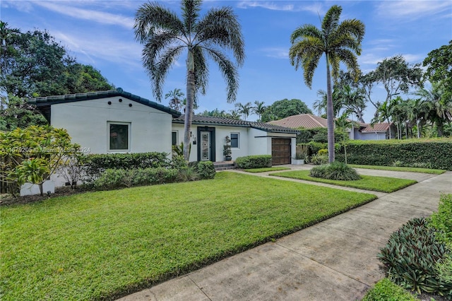 mediterranean / spanish-style home featuring a front yard and a garage