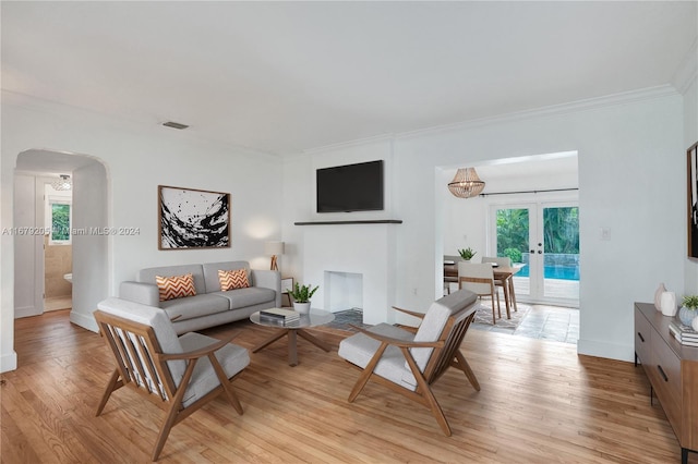 living room featuring french doors, ornamental molding, and light wood-type flooring