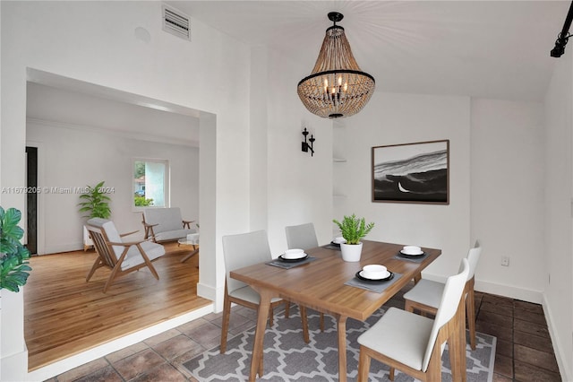 dining area featuring dark wood-type flooring, a notable chandelier, and lofted ceiling