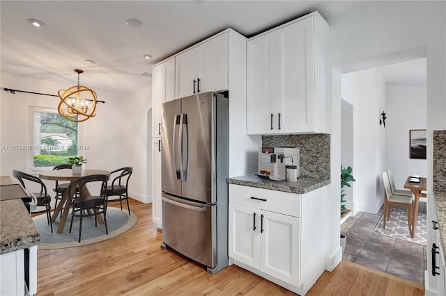 kitchen with white cabinetry, stainless steel fridge, light wood-type flooring, and pendant lighting