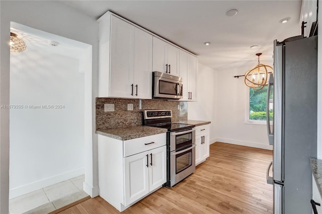 kitchen featuring appliances with stainless steel finishes, an inviting chandelier, white cabinetry, and light hardwood / wood-style floors