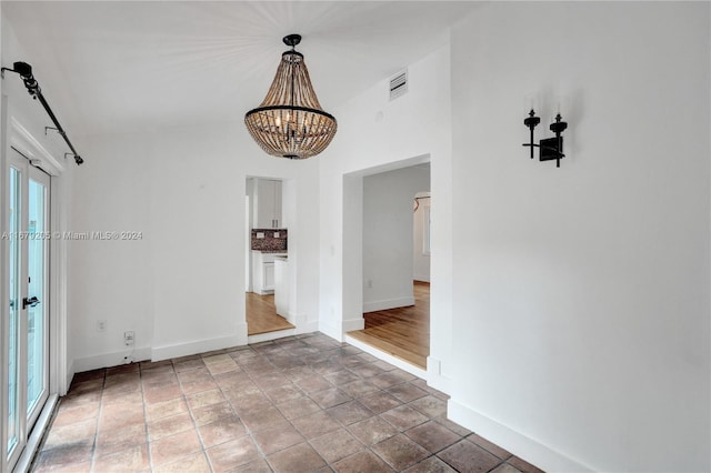 unfurnished room with hardwood / wood-style flooring and a notable chandelier