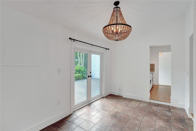 empty room featuring french doors and a chandelier