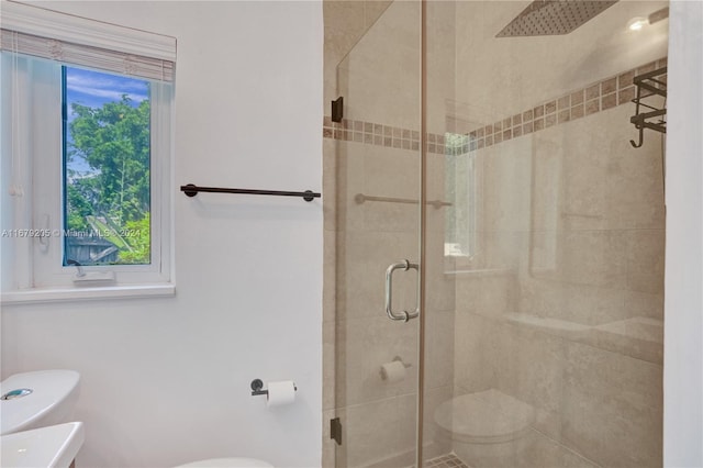 bathroom featuring a shower with door and toilet