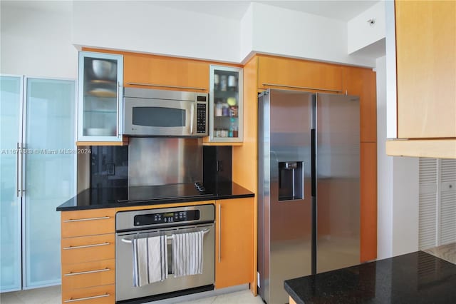 kitchen with decorative backsplash, stainless steel appliances, and dark stone counters