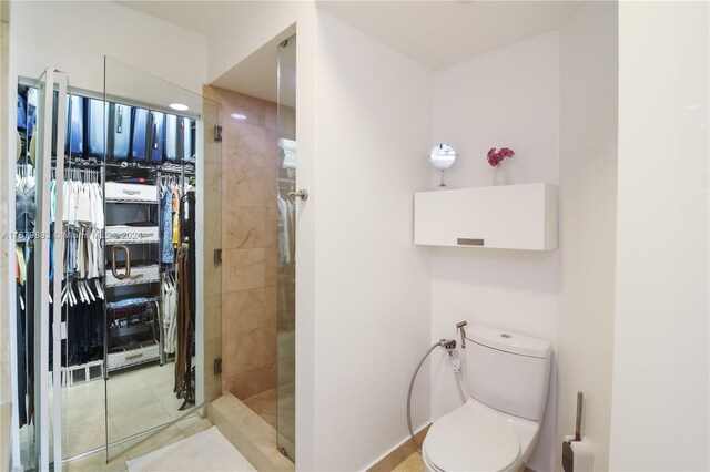 bathroom featuring toilet, an enclosed shower, and tile patterned flooring