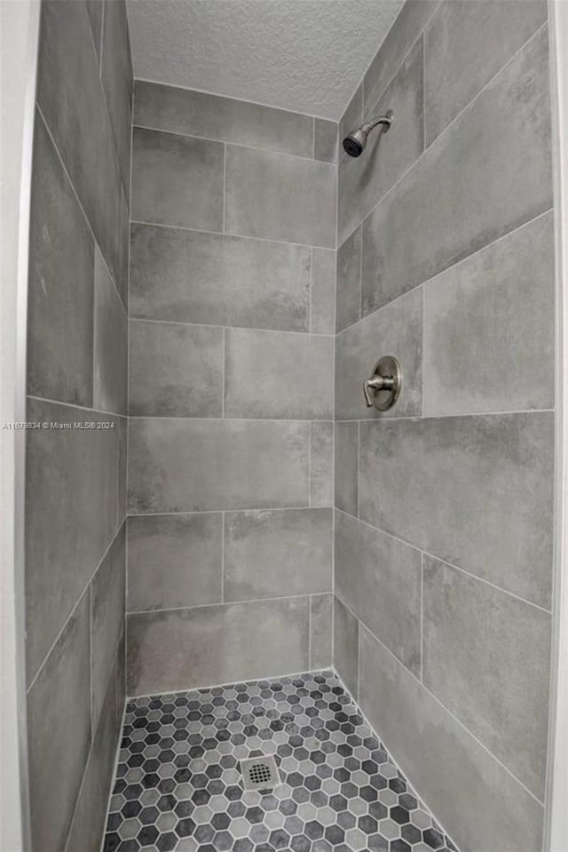 bathroom with tiled shower and a textured ceiling