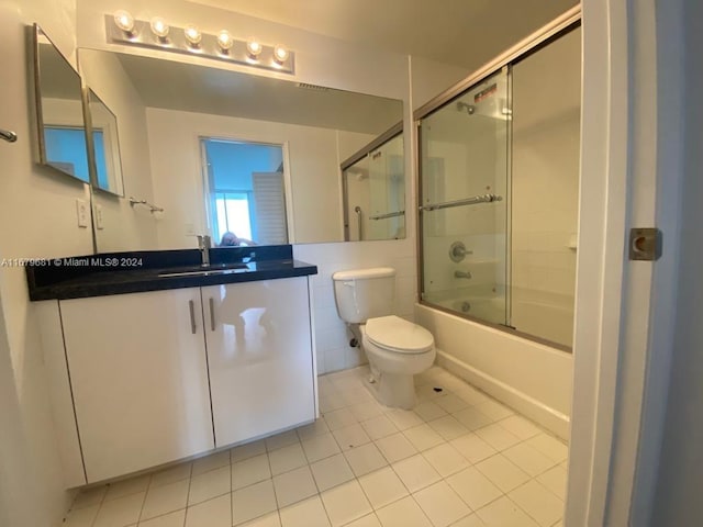 full bathroom featuring vanity, combined bath / shower with glass door, toilet, and tile patterned flooring