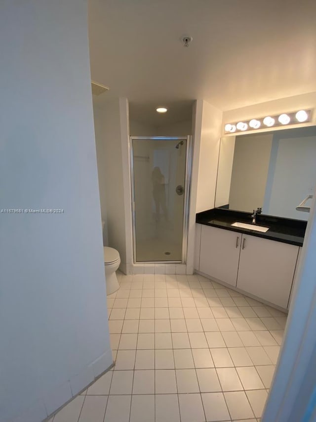 bathroom featuring vanity, toilet, tile patterned floors, and a shower with door