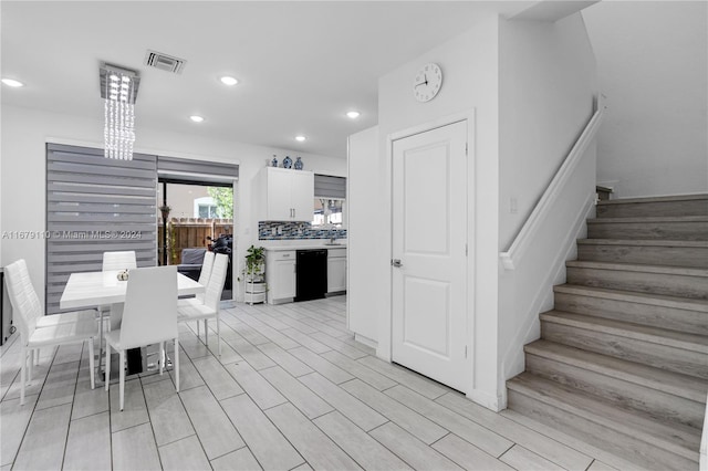 kitchen with tasteful backsplash, a breakfast bar, white cabinetry, dishwasher, and light hardwood / wood-style floors