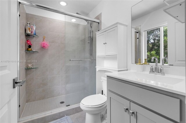 bathroom with vanity, a shower with shower door, toilet, and tile patterned floors