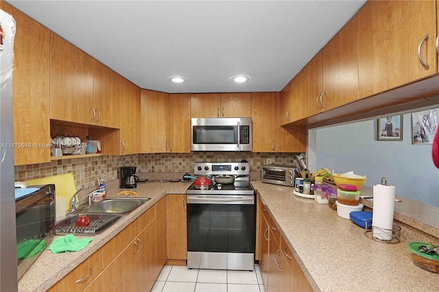 kitchen featuring appliances with stainless steel finishes, tasteful backsplash, sink, and light tile patterned floors