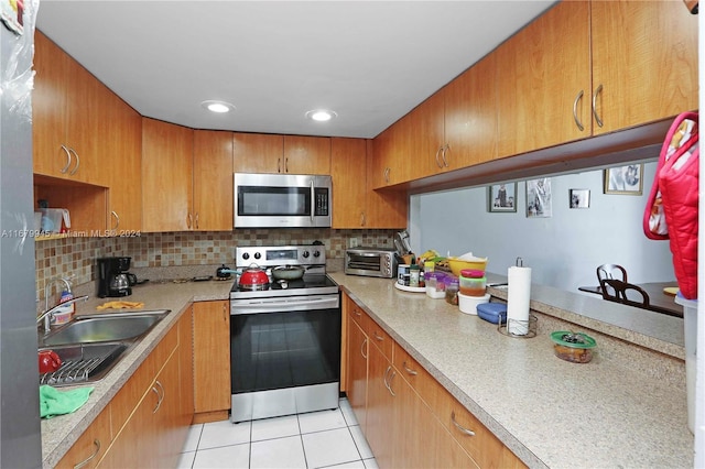 kitchen featuring backsplash, stainless steel appliances, sink, and light tile patterned flooring