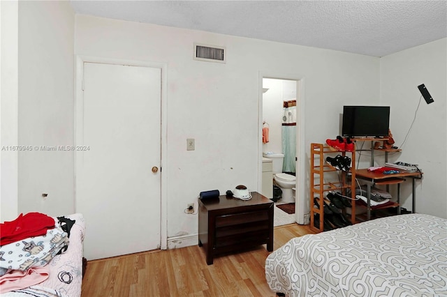 bedroom with light hardwood / wood-style flooring, a textured ceiling, and ensuite bathroom