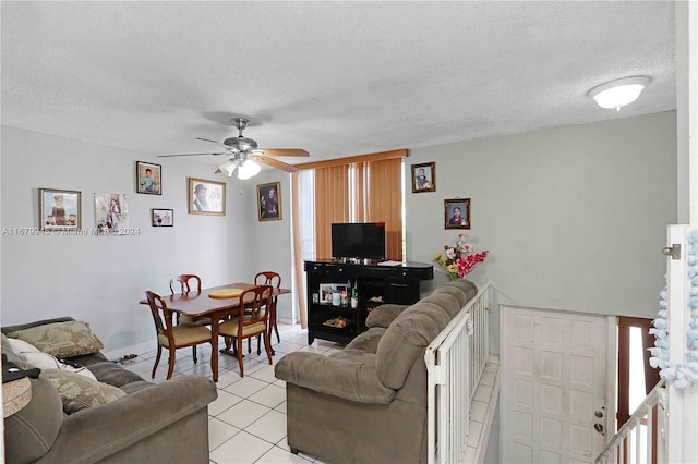 living room featuring a textured ceiling, light tile patterned floors, and ceiling fan