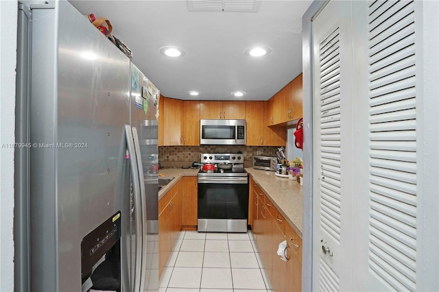 kitchen featuring light stone countertops, decorative backsplash, appliances with stainless steel finishes, and light tile patterned floors