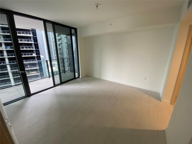 empty room with light hardwood / wood-style floors and a wall of windows