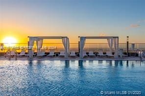 pool at dusk featuring a water view