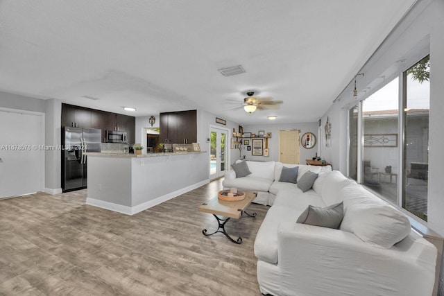 living room featuring light hardwood / wood-style floors, a wealth of natural light, and ceiling fan