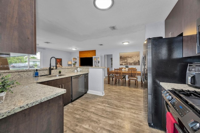 kitchen featuring sink, stainless steel appliances, dark brown cabinets, and light hardwood / wood-style flooring