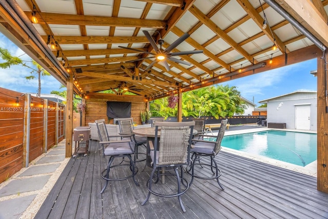 wooden deck with a fenced in pool and ceiling fan