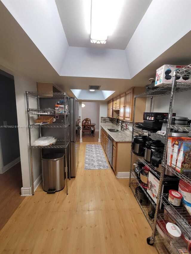 kitchen with sink, a raised ceiling, separate washer and dryer, light hardwood / wood-style flooring, and appliances with stainless steel finishes