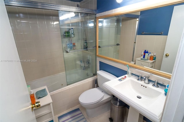 full bathroom featuring toilet, sink, tile patterned flooring, and combined bath / shower with glass door