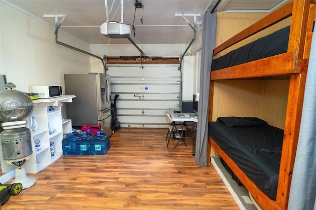 garage featuring stainless steel fridge with ice dispenser, a garage door opener, and wood walls