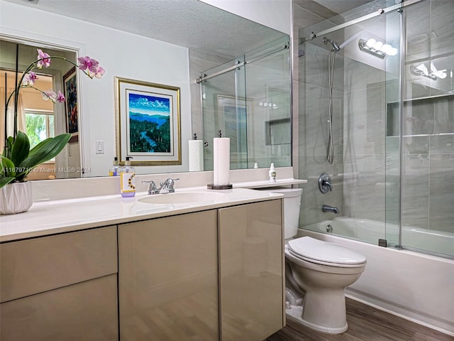 full bathroom with hardwood / wood-style floors, combined bath / shower with glass door, a textured ceiling, toilet, and vanity