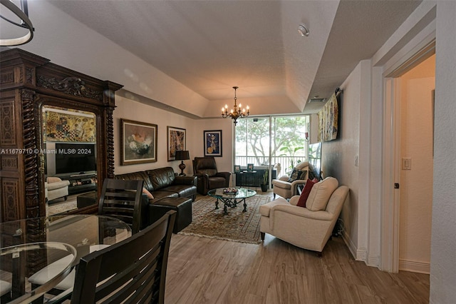 living room featuring a notable chandelier, light wood-type flooring, and vaulted ceiling