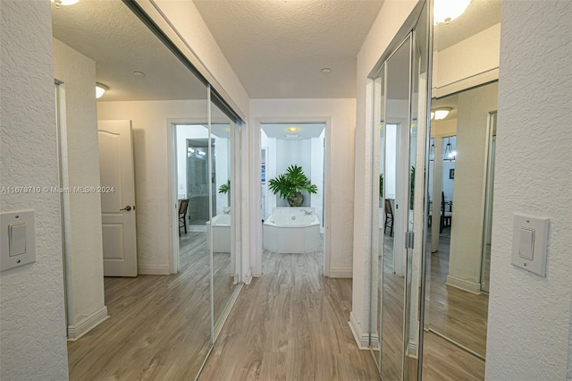 corridor featuring a textured ceiling and light wood-type flooring