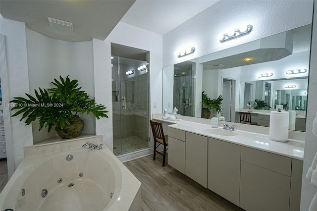 bathroom featuring vanity, hardwood / wood-style flooring, a textured ceiling, and shower with separate bathtub