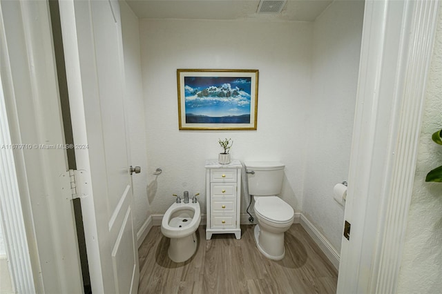 bathroom with a bidet, toilet, and hardwood / wood-style flooring