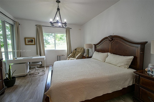 bedroom featuring hardwood / wood-style floors, multiple windows, and a chandelier