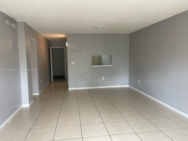 tiled empty room with a textured ceiling