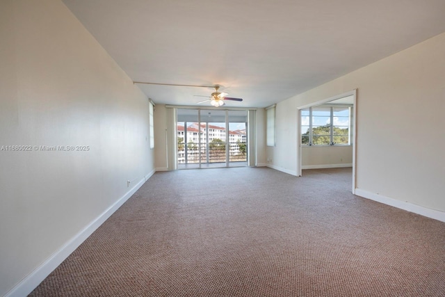 carpeted spare room with a wealth of natural light, expansive windows, and ceiling fan