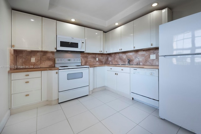 kitchen with tasteful backsplash, white cabinetry, sink, and white appliances