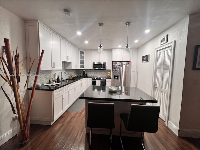 kitchen with a kitchen island, sink, white cabinets, pendant lighting, and appliances with stainless steel finishes