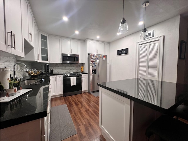 kitchen with stainless steel appliances, dark hardwood / wood-style flooring, pendant lighting, and white cabinets