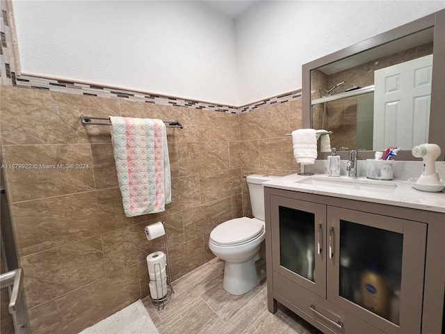 bathroom featuring tile walls, vanity, a shower with shower door, and toilet