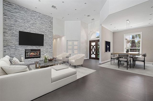 living room with crown molding, a fireplace, and a towering ceiling